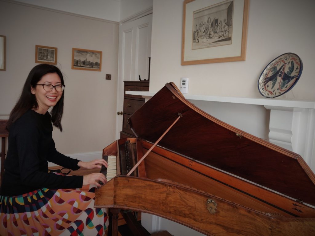 A smiling woman sat at an antique keyboard.