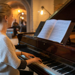 Woman sat playing at grand piano