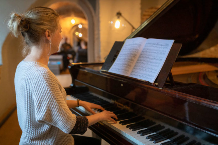 Woman sat playing at grand piano