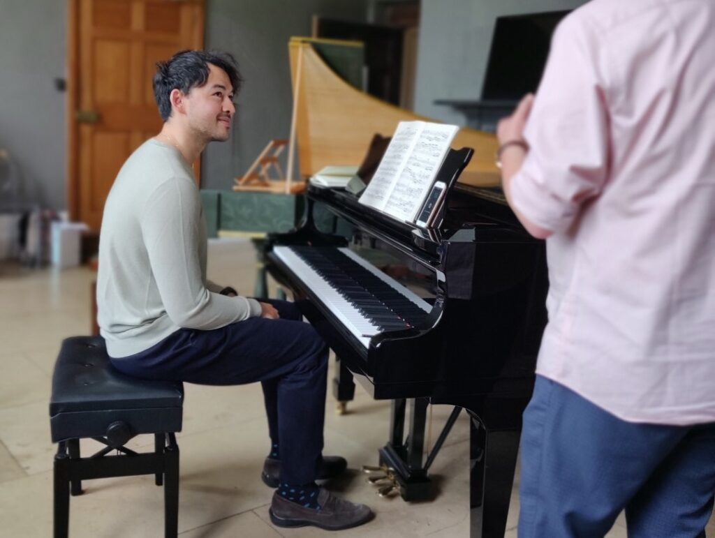 Man sitting at Steinway piano listening to tutor