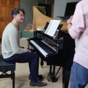 Man sitting at Steinway piano listening to tutor