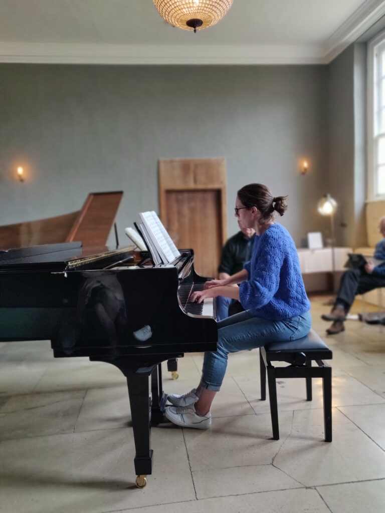 Woman playing Steinway piano in front of a small group of people