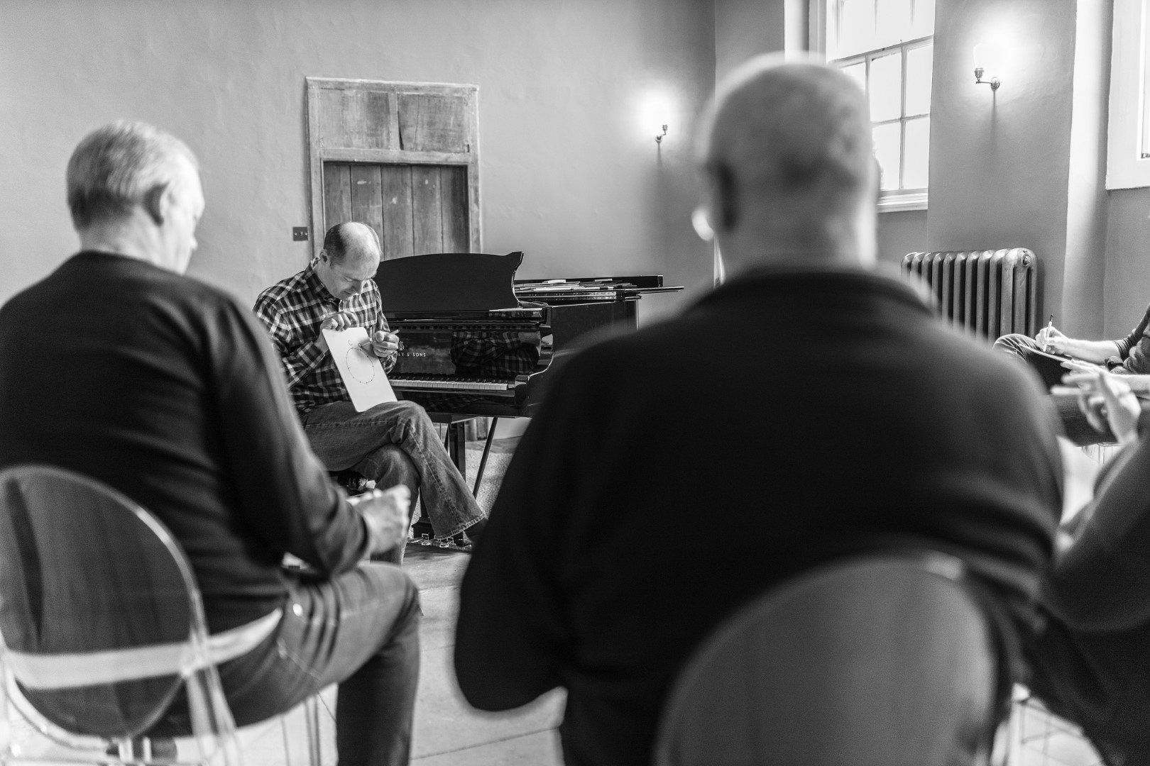 David Hall teaching adults in Finchcocks recital room, sat at Steinway with a mini white board.