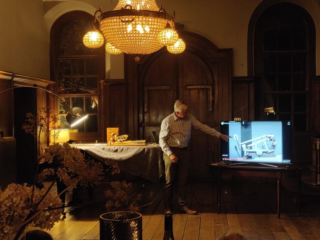 Stephen Carroll-Turner giving a talk in main hall, pointing to a screen with piano hammer on