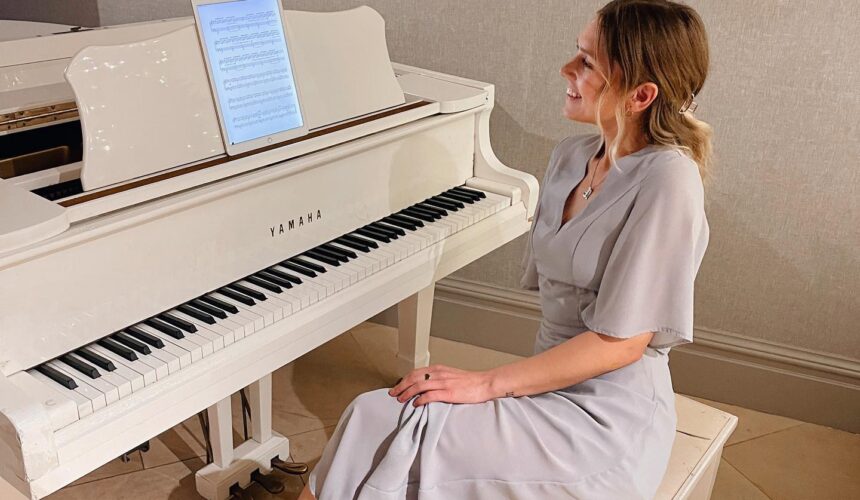 Emilija Ausraite sat at a white Yamaha grand piano looking at the music on her iPad